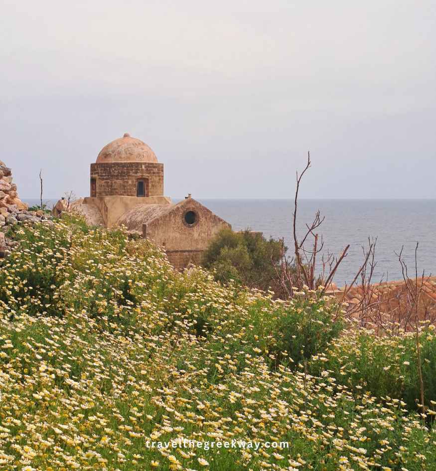 Ancient stone church surrounded by spring wildflowers in Monemvasia, Peloponnese Greece.