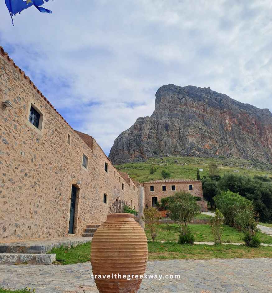 A traditional stone hotel building below the towering cliff of Monemvasia, Peloponnese Greece.