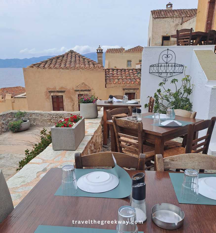 Set dinner tables at an outdoor terrace overlooking the sea in medieval Monemvasia, Peloponnese Greece.