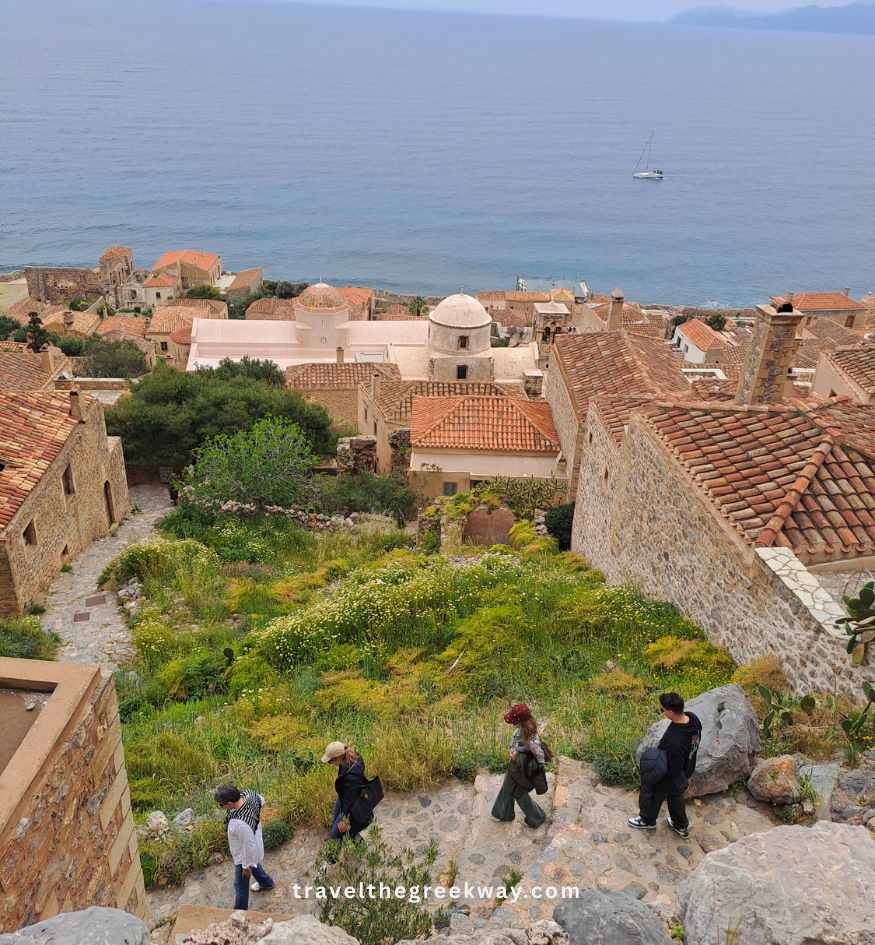 Tourists walking down a steep, winding path from the upper town of Monemvasia, Peloponnese Greece.