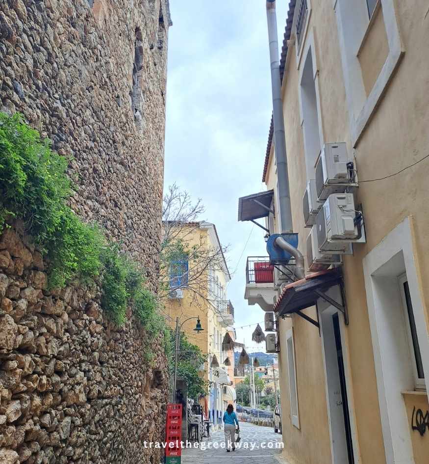 Narrow stone-paved alley between traditional houses and an old stone wall in the upper town of Gythio.