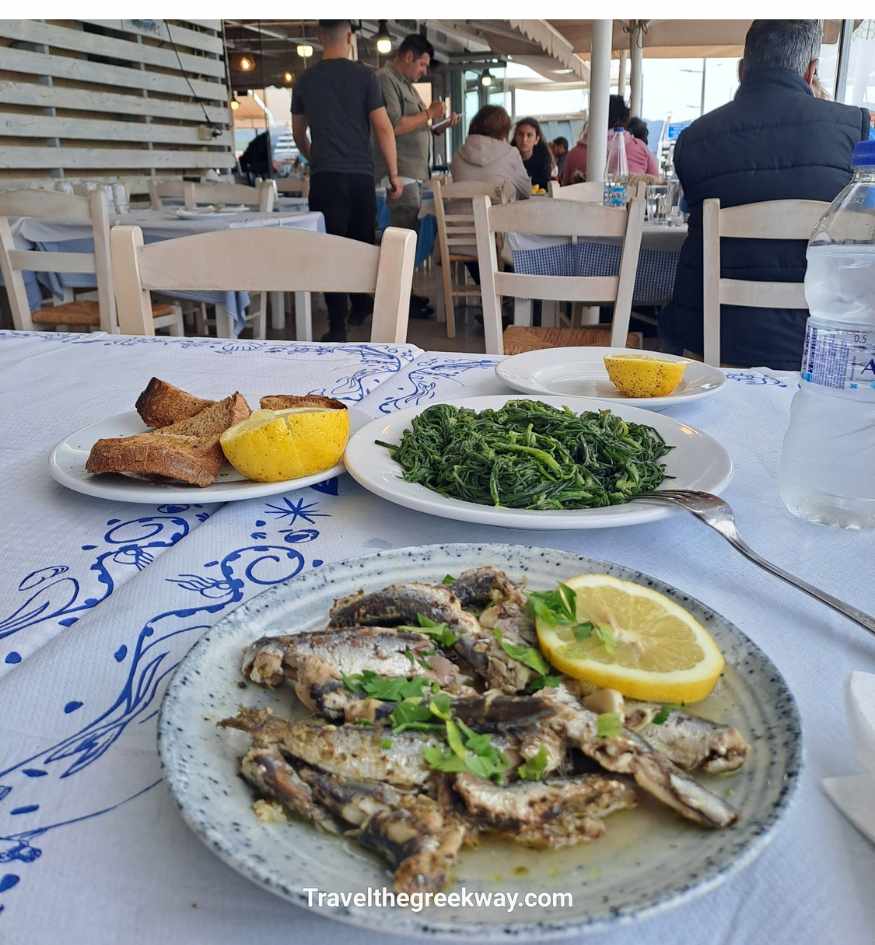 Traditional Greek meal with small fried fish, boiled greens, lemon and toasted bread at a taverna in Gythio.