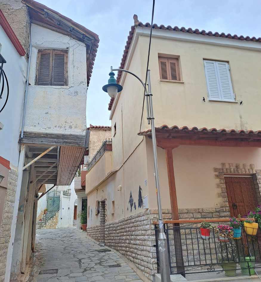 Traditional houses lining a narrow stone-paved uphill alley in the old neighborhoods of Gythio, Greece.