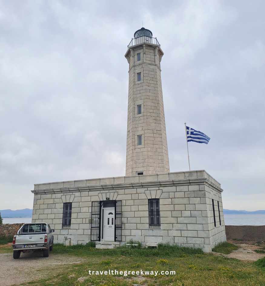 Historic stone lighthouse of Gythio with the Greek flag beside it on Kranae Island.