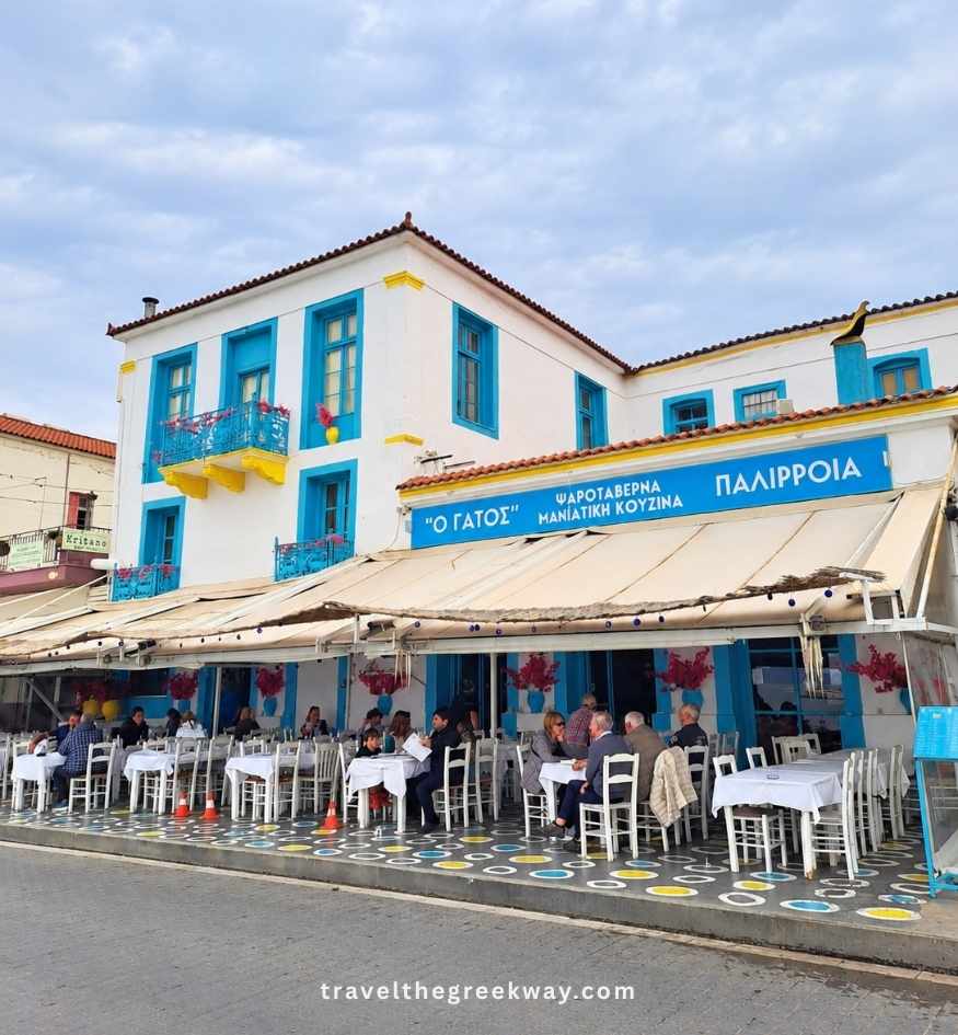 O Gatos traditional fish taverna with blue-and-white decor and outdoor tables along the waterfront in Gythio, Greece.