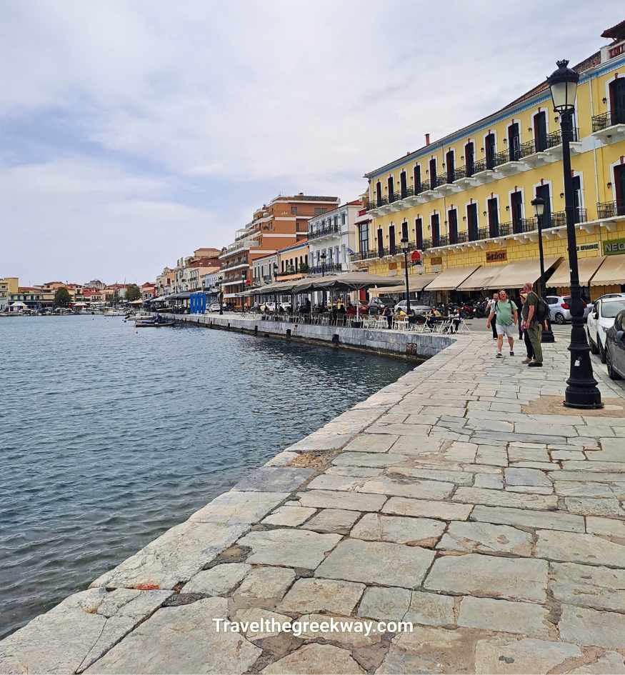 Gythio waterfront promenade with colorful neoclassical buildings, outdoor cafes and the harbor beside the sea.
