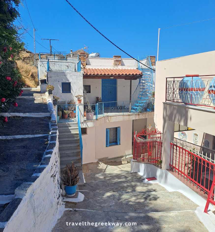 Traditional houses with colorful doors, balconies and steep stone steps along a residential lane in Ioulida, Kea island, Greece.