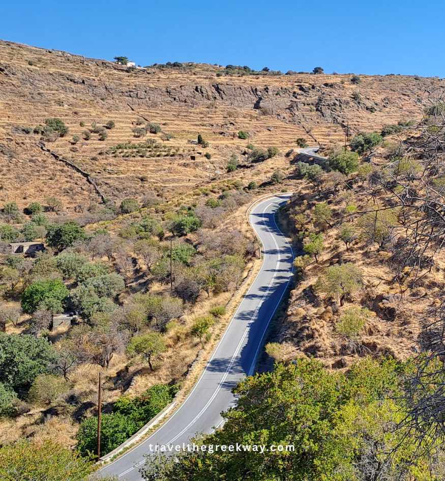 Winding paved road crossing the dry, terraced hills and rural landscape of Kea island in the Cyclades, Greece.