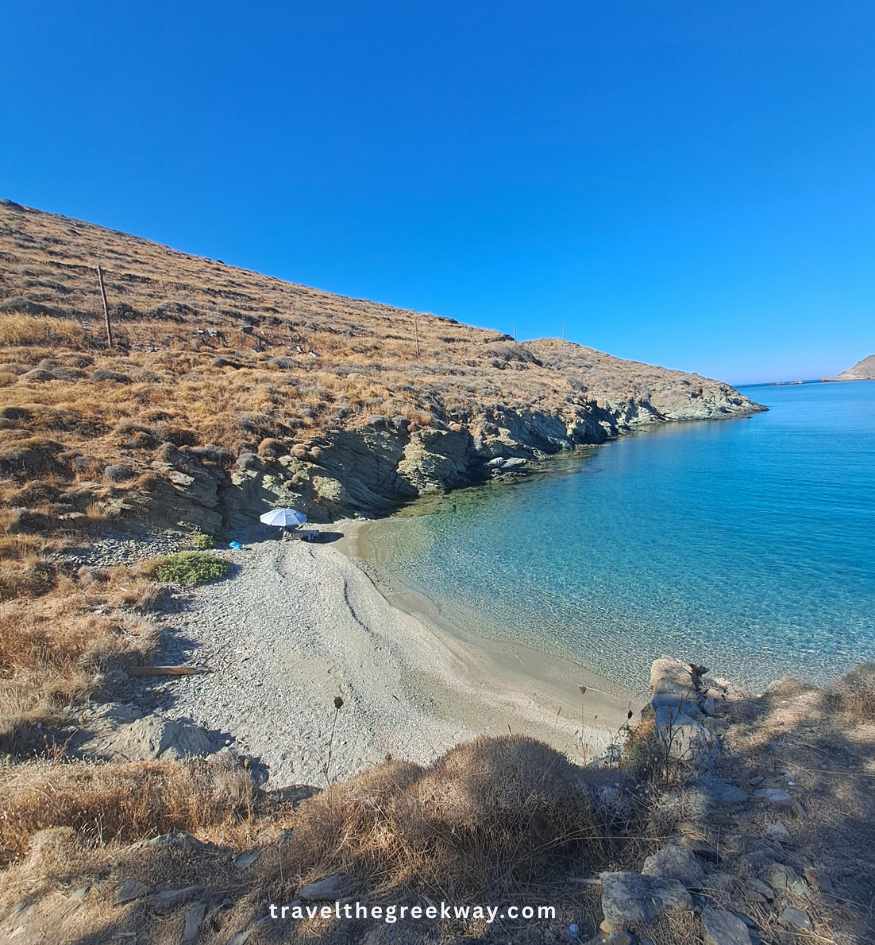 Small secluded sandy and pebble beach with crystal-clear turquoise water and rocky hills near Otzias on Kea island, Greece.