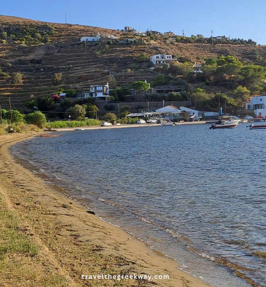 Quiet shoreline and small boats in the sheltered bay of Vourkari, with traditional houses scattered across the hills of Kea island, Greece.